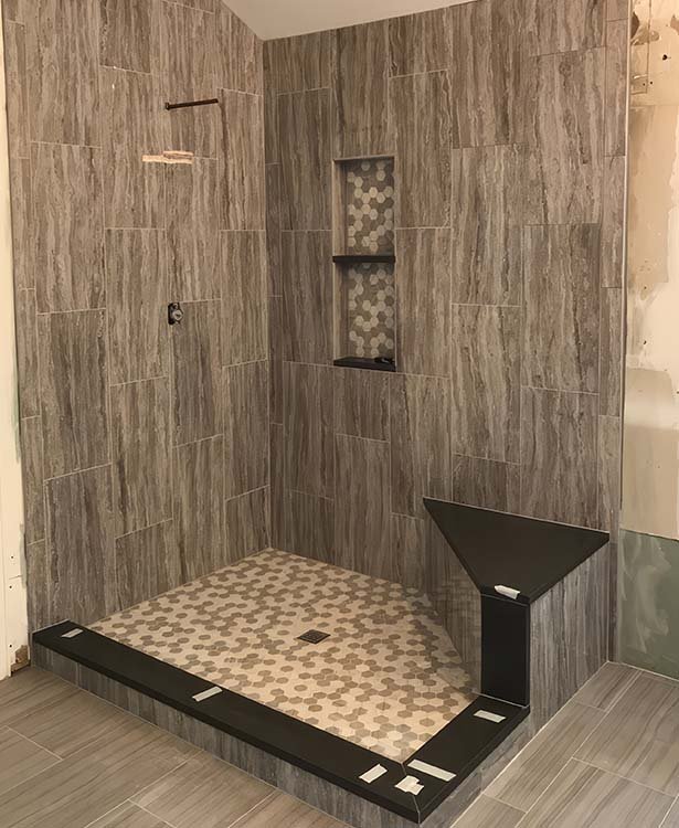 Custom walk-in shower with wood-look tile, niche and corner bench