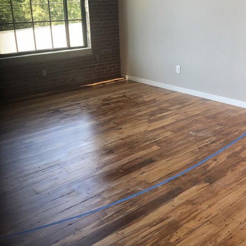 Newly refinished hardwood floor in a loft with brick wall