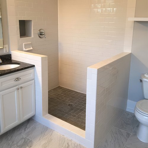 Walk-in shower with subway tile and dark mosaic floor