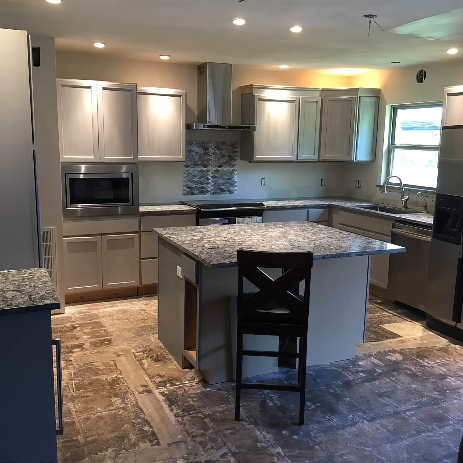 Remodeled kitchen with grey shaker cabinets and granite island
